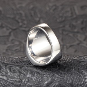 Detailed close-up of a polished wide-band stainless steel ring with a smooth silver finish