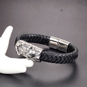 Detailed close-up of men's braided leather bracelet with silver scorpion skull charm