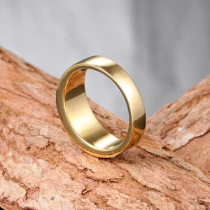 Bague large polie en acier doré pour hommes présentée sur un support en écorce naturelle