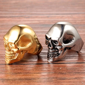Detailed macro view of gold and silver skull rings on a rustic wood background