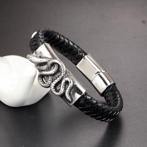 Detail of woven black leather bracelet featuring a vintage silver snake charm on a stand