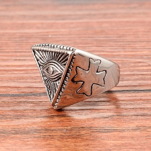Vintage stainless steel eye of providence ring with embossed cross on wood background