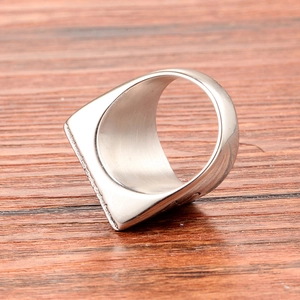 Detailed view of silver stainless steel square signet ring on a wooden surface