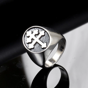 Macro shot of punk style stainless steel signet ring with silver cross on black surface