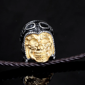 Punk style stainless steel skull aviator ring with gold face and helmet on black background