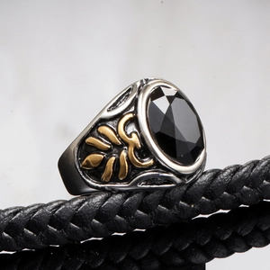Macro detail of men's vintage silver ring with gold leaf accents and black gemstone