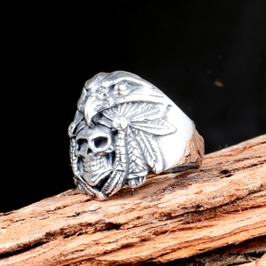 Macro shot of vintage skull and eagle ring on rustic wood with feather details