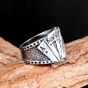 Detail of vintage 316 stainless steel poker ring with A-K-Q cards on tree bark