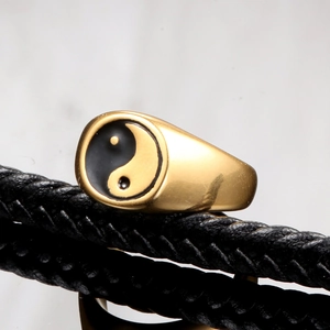 Macro detail of golden stainless steel ring featuring a black and white Yin Yang symbol