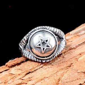 Détail macro d'une bague étoile punk au fini vintage sur fond de bois naturel chic