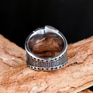 Macro detail of retro stainless steel poker ring with industrial mesh texture on bark
