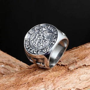 Vintage stainless steel St. Michael signet ring displayed on a natural wood piece