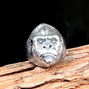 Macro shot of detailed gorilla head stainless steel ring on a rustic wood bark texture