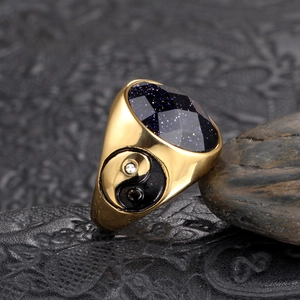 Macro detail of men's gold stainless steel ring with blue stone and yin yang design
