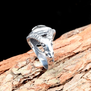 Bague gothique tête de bélier en acier inoxydable argenté sur fond bois texturé