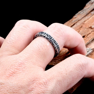 Detail of vintage stainless steel S-shape ring with scrollwork engraving on hand