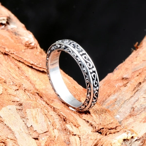 Vintage stainless steel S-shape ring with floral relief on textured wood background
