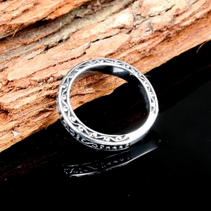 Vintage stainless steel S-shape ring with scroll patterns on wood and black mirror background
