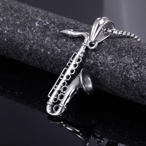 Detailed macro view of a polished stainless steel saxophone pendant with square bead chain