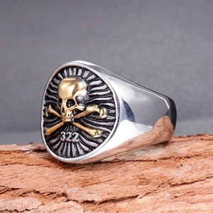 Macro detail of silver stainless steel pirate ring featuring golden skull and 322 engraving