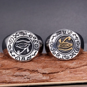 Detailed macro of vintage titanium steel Eye of Horus rings on natural wood