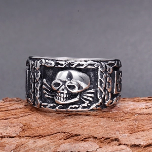 Close-up of vintage silver skull ring with chain texture and cross detailing on wood
