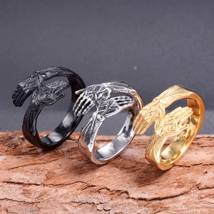 Fashionable men's stainless steel hug rings in black, silver, and gold on wood