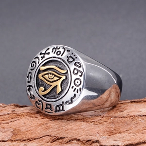 Detail of vintage stainless steel signet ring with golden Eye of Horus on rustic wood bark