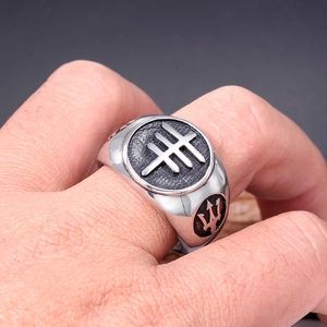 Macro shot of silver stainless steel ring with trident emblem and relief symbol