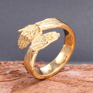 Detailed close-up of a gold hand-shaped ring featuring realistic texture on a wood bark