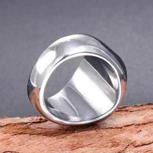 Polished liquid metal texture ring with irregular organic ripples on rustic wood