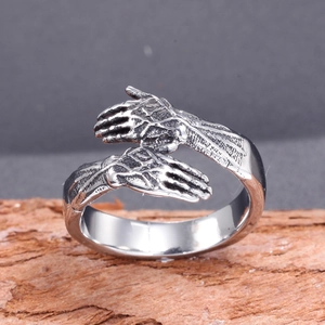 Unique stainless steel hugging hands open ring shown on a rustic wood background