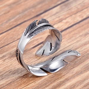Vintage stainless steel feather wrap ring with retro oxidized silver finish on wood