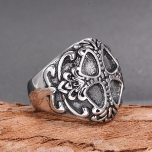 Close-up of vintage stainless steel ring with gothic hollow patterns on wood base