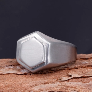 Bague chevalière hexagonale en acier inoxydable brossé pour homme sur bois rustique