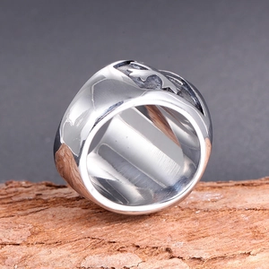 Detailed view of men's stainless steel cross ring with embossed totem on wood