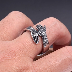 Macro shot of vintage stainless steel hugging hands ring with detailed texture