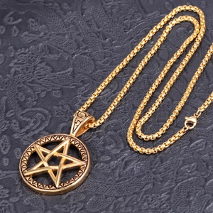 Detail of gold-plated stainless steel pentagram pendant on black textured background