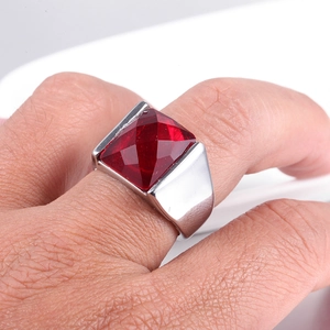 Detailed view of a men's stainless steel ring with a large square red gemstone on finger