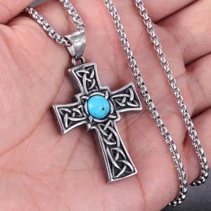 Close-up of titanium steel Celtic cross pendant with turquoise gem held in hand