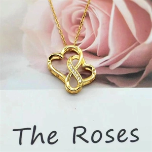 Detailed view of gold infinity double heart pendant with sparkling cubic zirconia