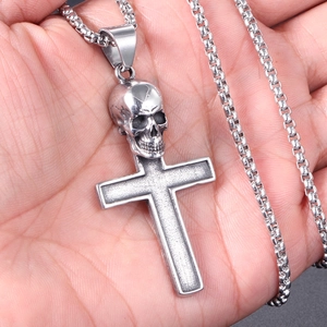 Macro view of a stainless steel skull cross pendant held in hand for size detail