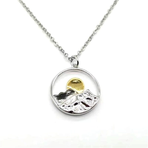 Artistic two-tone mountain and sun circular cutout pendant necklace on silver cross chain