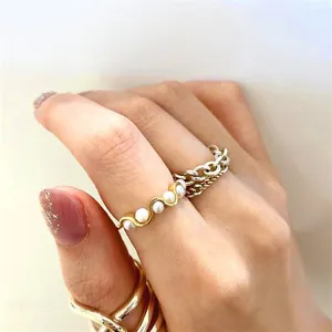 Stacked S925 silver rings set with pearls and wavy golden bands on model's hand