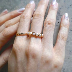 Detail of stacked gold rings with a wavy pearl band and a sparkling star ring