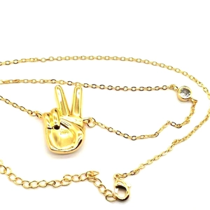 Detail of gold plated peace sign pendant necklace with zircon and lobster clasp