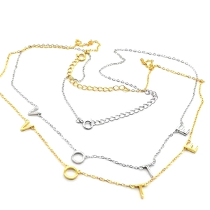 Detail of silver and gold VOTE necklaces with adjustable lobster clasp on white background
