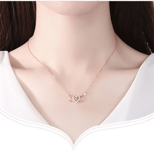 Détail d'un collier cœur et infini en or rose avec zircons porté par un mannequin réel