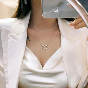 Close-up of S925 sterling silver heart pendant necklace worn with a white silk top