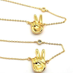 Close-up of gold-plated peace sign hand pendant with round zircon on O-chain necklace